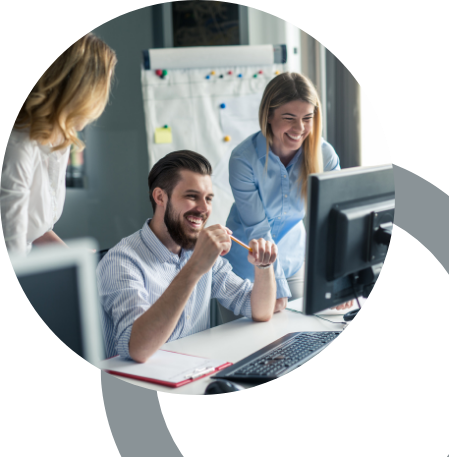 Trzy osoby, siedzące przy stole, pracujące przy komputerze